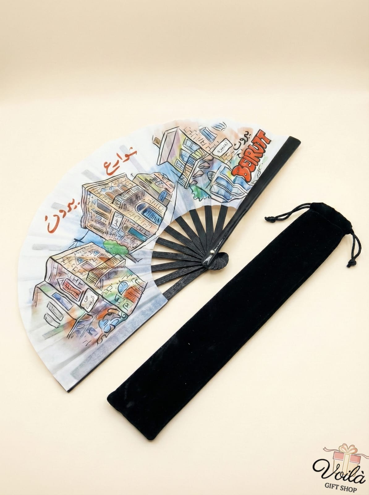 Decorative fan with artistic design and black carrying case on a beige background