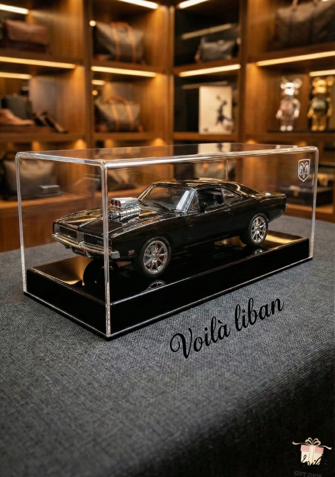 Model car in a clear display case with 'Voila liban' branding on a dark surface.