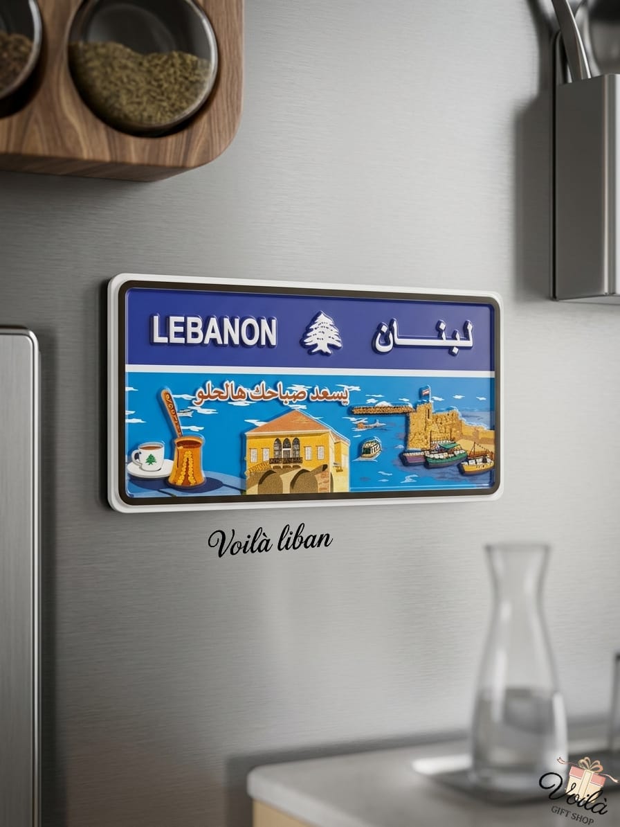 Decorative blue Lebanese license plate fridge magnet on a stainless steel surface, featuring a bright coastal scene with the Saida Sea Castle, a traditional stone house, a coffee rakwe, and the Arabic phrase Yis'ed sabahak ya helo.
