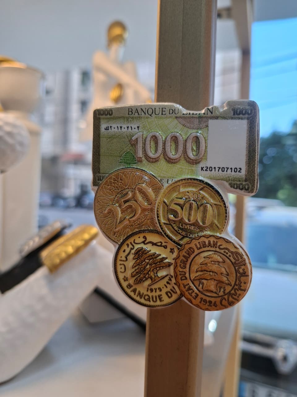 Three coins with banknote design on a stand, resembling Lebanese currency.