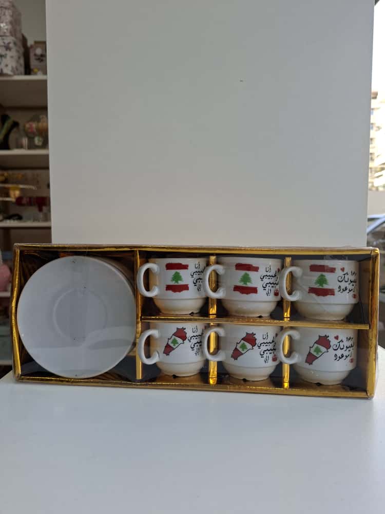 Set of six ceramic cups with saucers in a decorative box on a white surface.