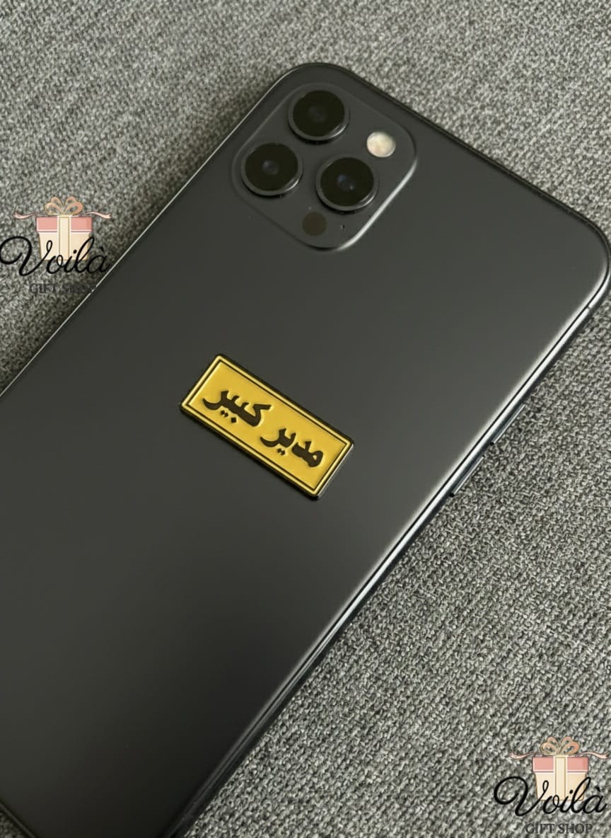 Black smartphone with a yellow label on a textured surface, branded 'Voila'.
