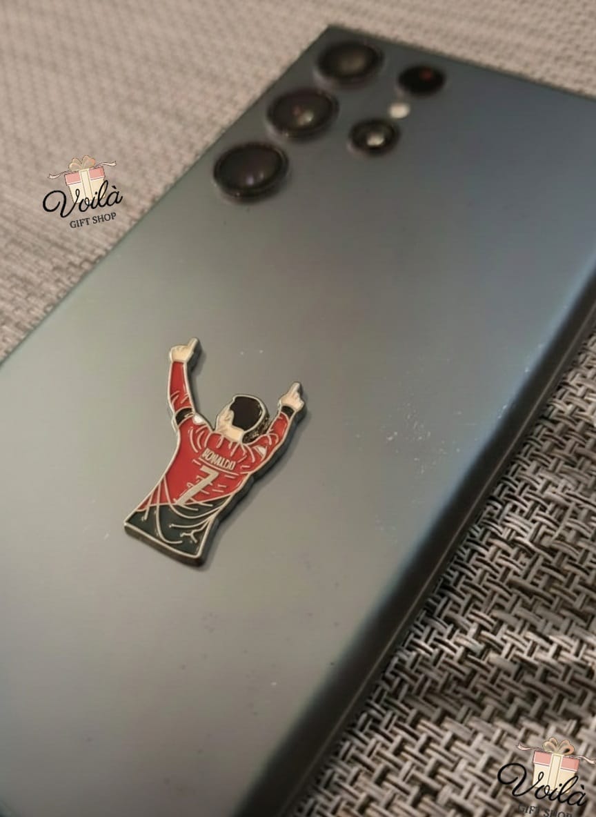 Phone case with a pin of a person in a red outfit on a textured surface