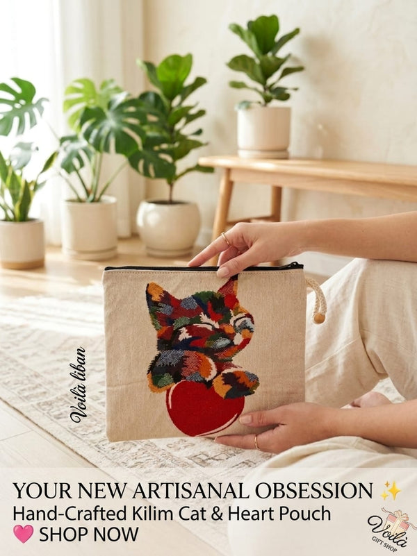 Woman sitting in a sunny room holding a premium hand-crafted kilim tapestry pouch featuring a colorful woven cat resting on a large red heart.