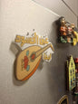 Fridge magnet with a lute design and Arabic text on a metallic surface.