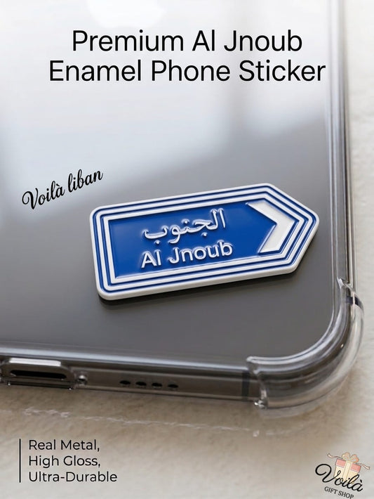 Premium blue metal enamel phone sticker shaped like a Lebanese street sign pointing right, featuring the text "Al Jnoub" in English and the Arabic script (الجنوب), attached to a clear phone case.
