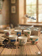 Set of hand-painted ceramic cups on a wooden table with coffee beans, in front of a blurred background.