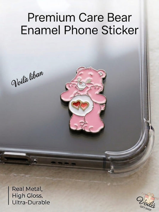 Premium pink metal enamel phone sticker shaped like a classic Care Bear (Love-a-Lot Bear) with two interlocking red hearts on its white belly, affixed to a clear smartphone case.