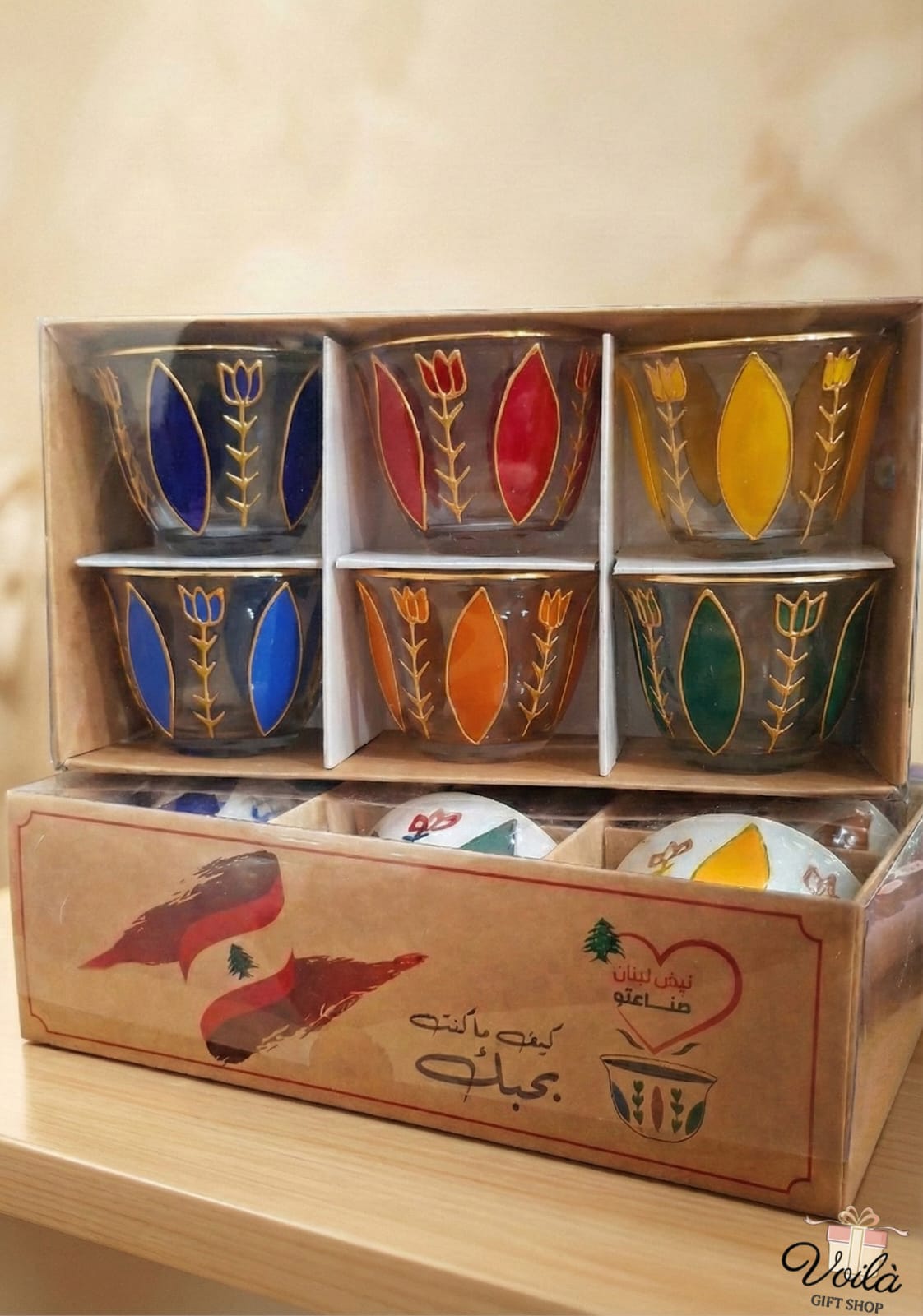 Set of colorful ceramic cups in a wooden box with decorative designs.