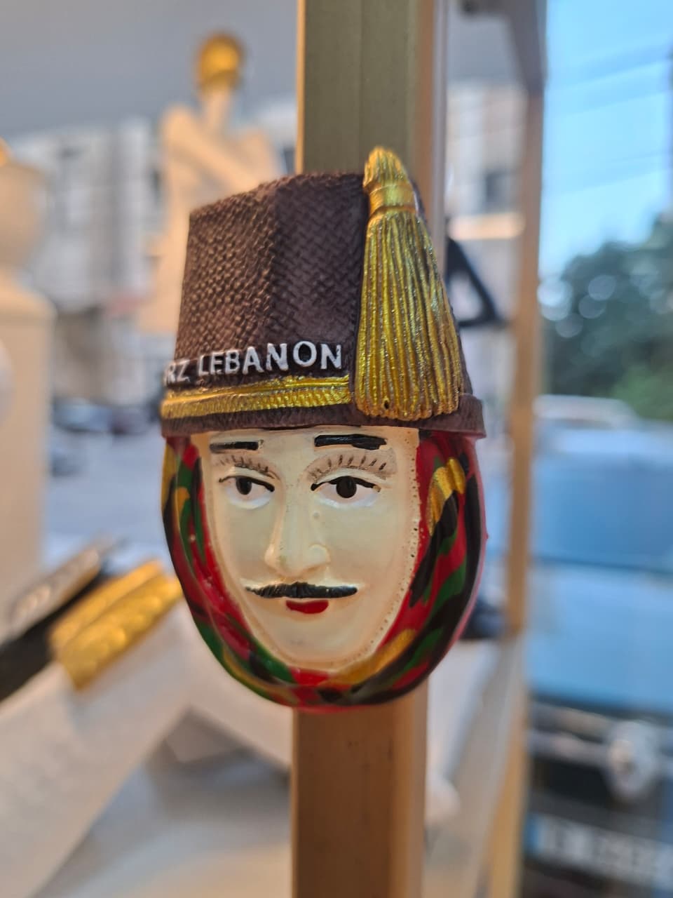 Decorative item with a face design and 'ARZ LEBANON' text on a stand.