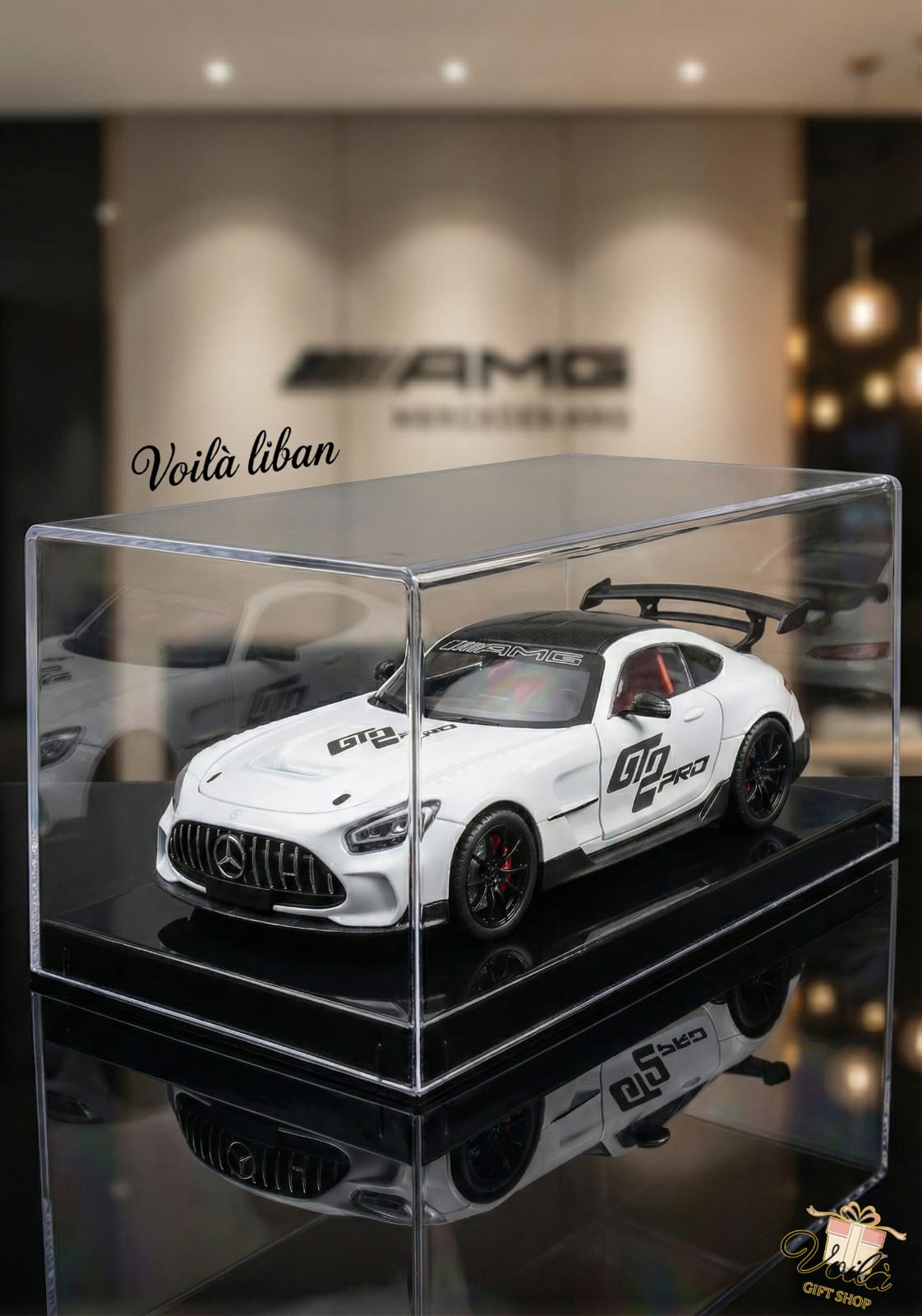 Model car in a transparent display case with AMG branding in the background