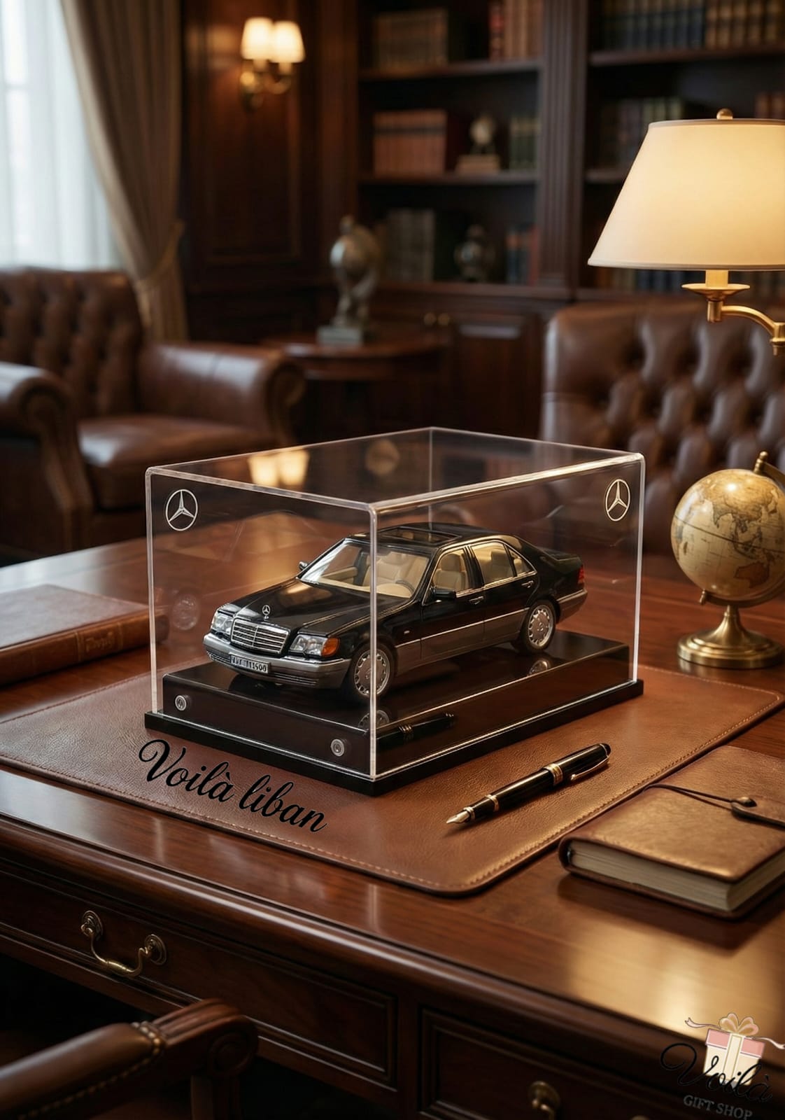 Model car in a clear display case on a wooden desk with a lamp and books in the background.