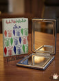 Compact mirror with a colorful case on a wooden surface