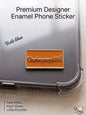 Premium rectangular orange and silver metal enamel phone sticker featuring the humorous Arabic phrase "أنا فاهم بس بستعبط!" written in elegant silver script, attached to a clear phone case.