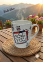 Steaming mug with Arabic text on a wooden table with a scenic background