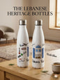 Two white bottles with Lebanese design elements on a wooden table.