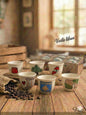 Set of ceramic cups with various designs on a wooden table, with 'Voila Liban' branding.