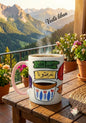 Decorative coffee mug with Arabic text on a wooden table with a mountainous landscape in the background.
