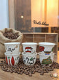 Set of ceramic cups with various designs and text on a wooden surface with coffee beans.