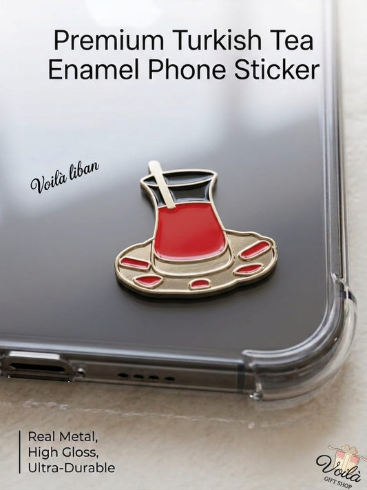 Premium metal enamel phone sticker shaped like a traditional Turkish tea glass (Istikan) filled with red tea on a gold saucer with red accents, featuring a small gold spoon, attached to a clear phone case.
