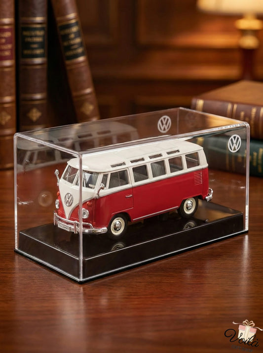 Red and white model van in a clear display case on a wooden surface with books in the background