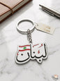 Keychain with Lebanese flag design and 'Voila Lebanon' branding on a marble surface.