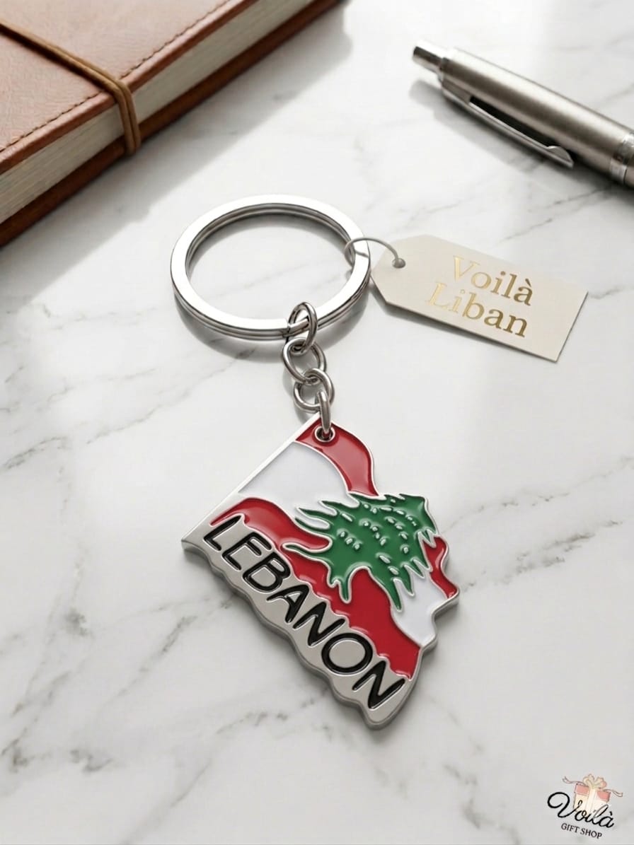 Keychain with Lebanese flag design on a marble surface with a notebook and pen.