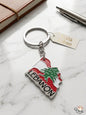 Keychain with Lebanese flag design on a marble surface with a notebook and pen.