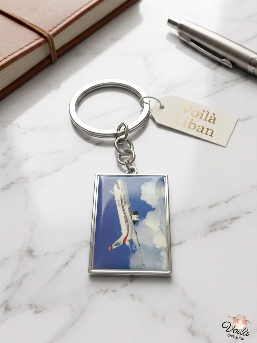 Keychain with airplane design on a marble surface with a pen and notebook.