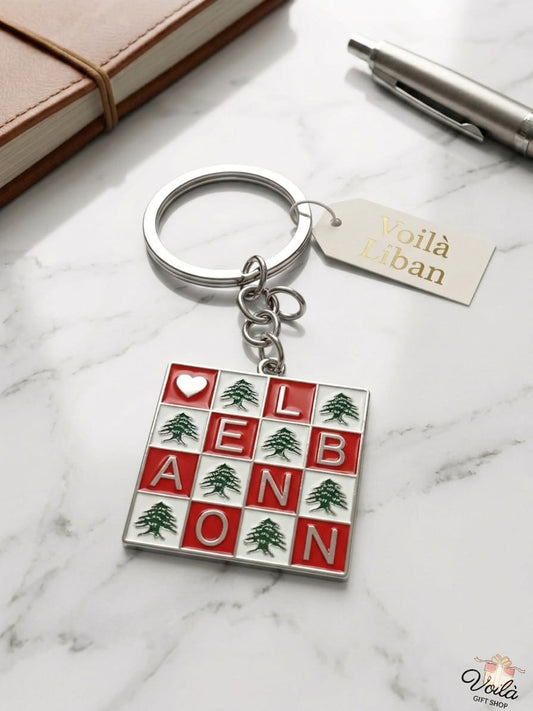 Keychain with 'Lebanon' design on a marble surface with a notebook and pen.