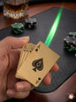 Hand holding gold playing cards with poker chips and a glass of whiskey on a table.