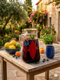 Hand-painted glass pitcher with Arabic calligraphy on a rustic wooden table in Lebanon