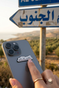 Al Janoub Khat Ahmar enamel sticker on a grey iPhone with a Lebanese road sign in the background