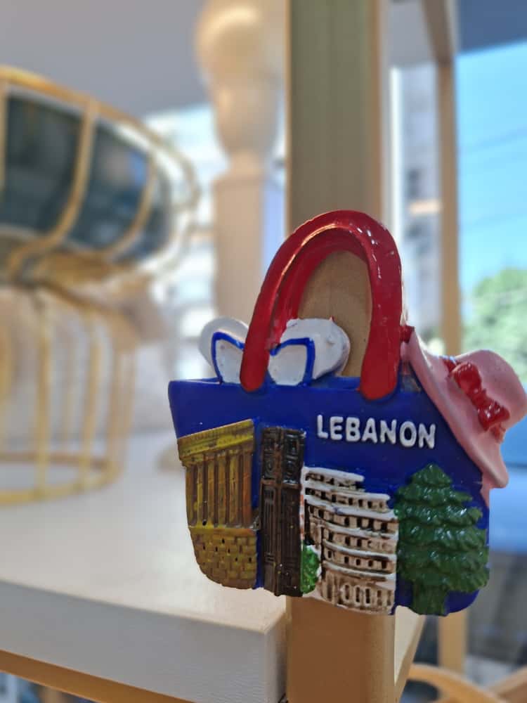 Fridge magnet shaped like a bag with 'Lebanon' text and building designs on a blurred background