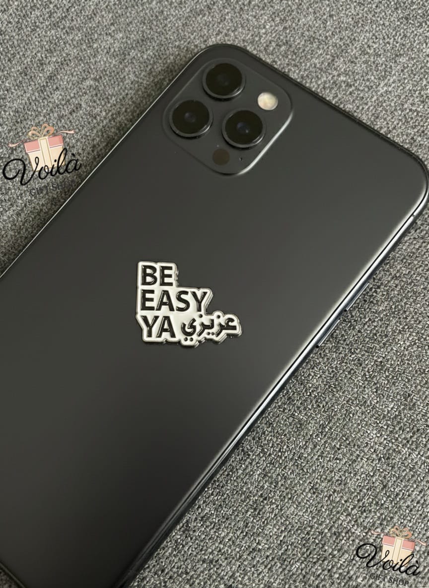 Black smartphone with 'BE EASY YA' text on a textured gray surface
