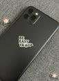 Black smartphone with 'BE EASY YA' text on a textured gray surface