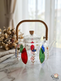 Hand-painted glass teapot with colorful motifs and a bamboo handle on a marble table