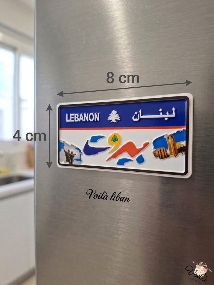 Decorative Beirut Lebanon license plate fridge magnet measuring 8cm by 4cm, featuring the Lebanese cedar, stylized Beirut Arabic text, Raouche Rocks, and Martyrs' Monument, placed on a stainless steel refrigerator.