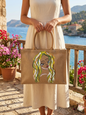 Hand-painted jute tote bag with artistic woman portrait held on a Mediterranean balcony in Lebanon