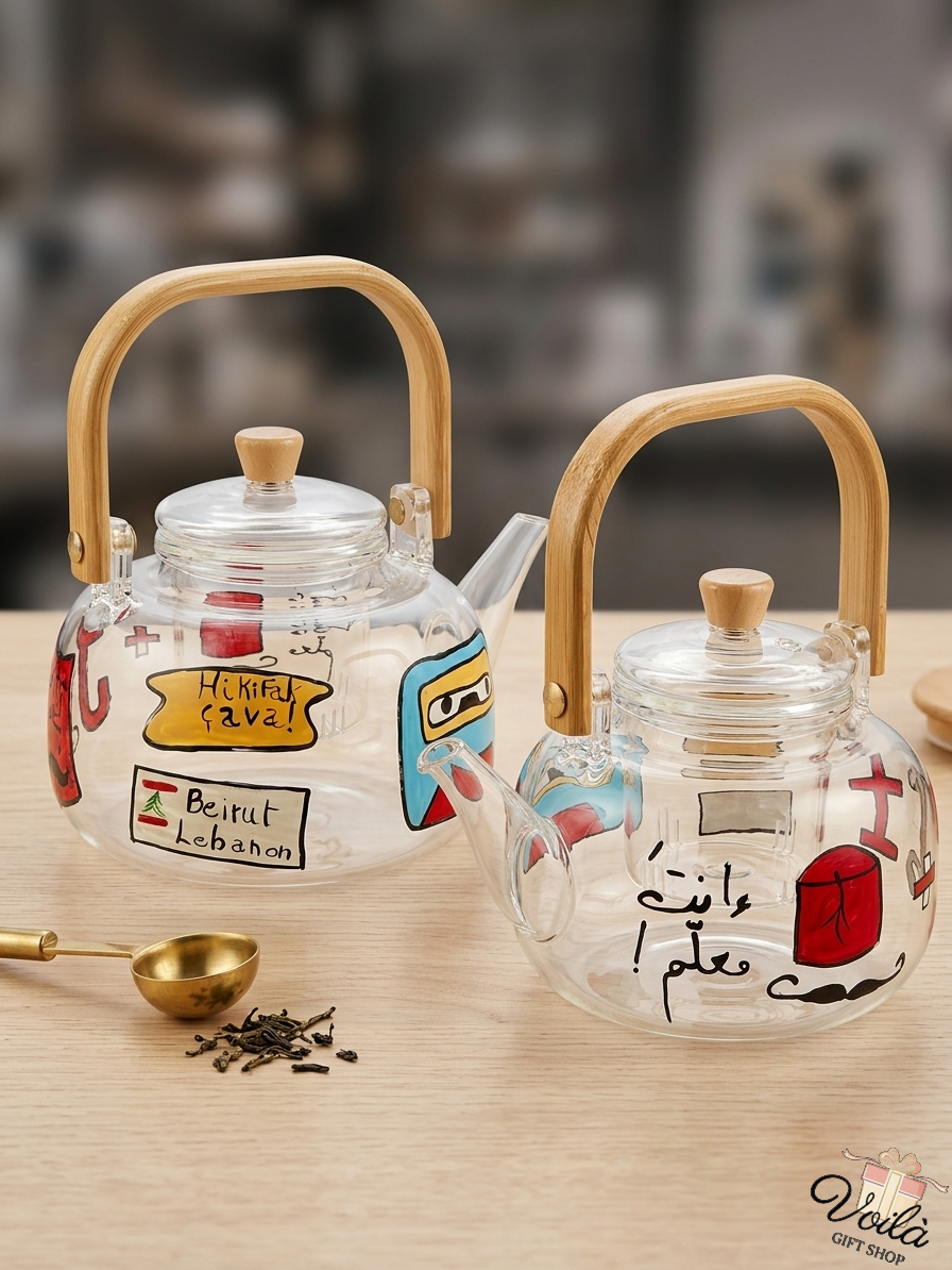 Two hand-painted glass teapots with bamboo handles featuring Lebanese cultural phrases and symbols