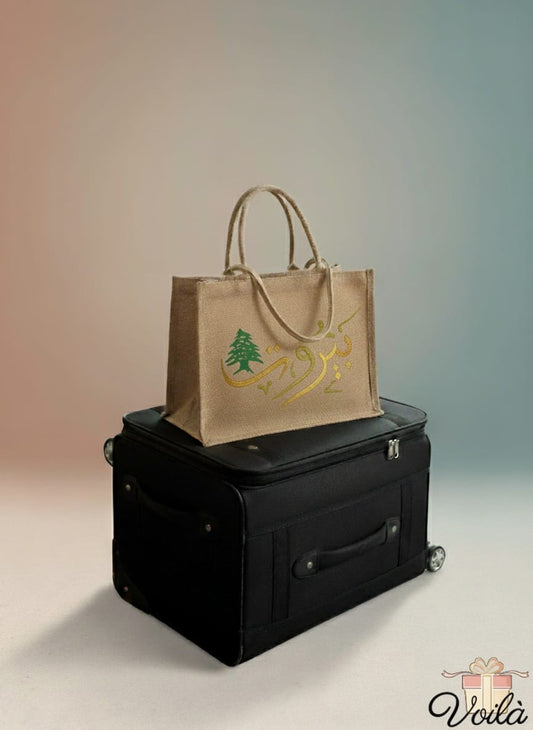 Brown tote bag with a logo on top of a black suitcase against a gradient background
