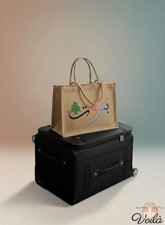 Brown tote bag with colorful design on a black suitcase against a gradient background