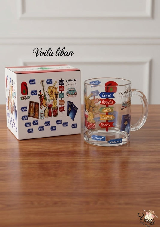 Clear glass mug with colorful designs on a wooden surface next to its packaging box.