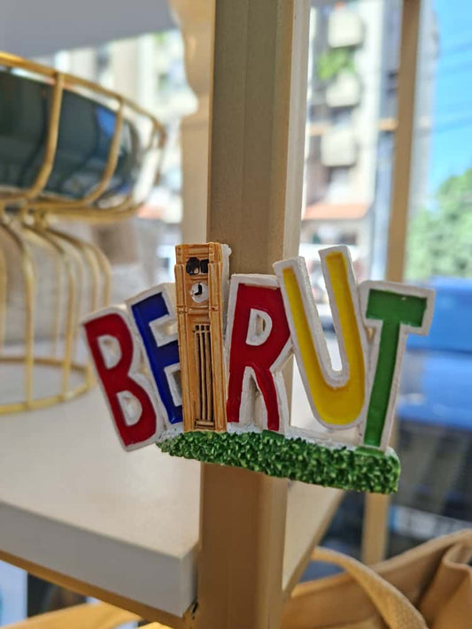Colorful 'Beirut' sign with a clock tower design on a stand.