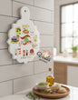 Decorative cutting board with illustrations and text on a kitchen counter.