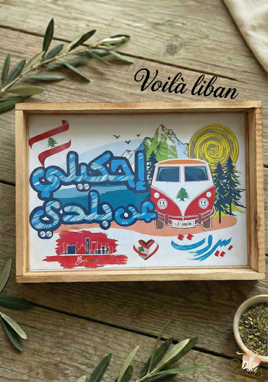 Decorative tray with a colorful illustration of a van, mountains, and text on a wooden surface.