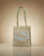Beige tote bag with Arabic text on a beige background