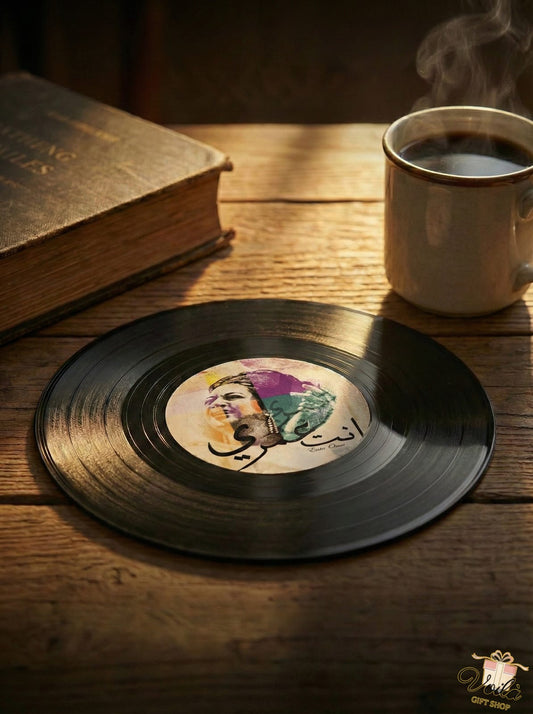 Vinyl record with a colorful face illustration on a wooden table with a cup of coffee and a book.