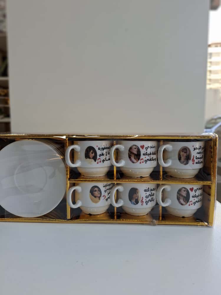 Set of six white mugs with printed designs in a gold box on a white background