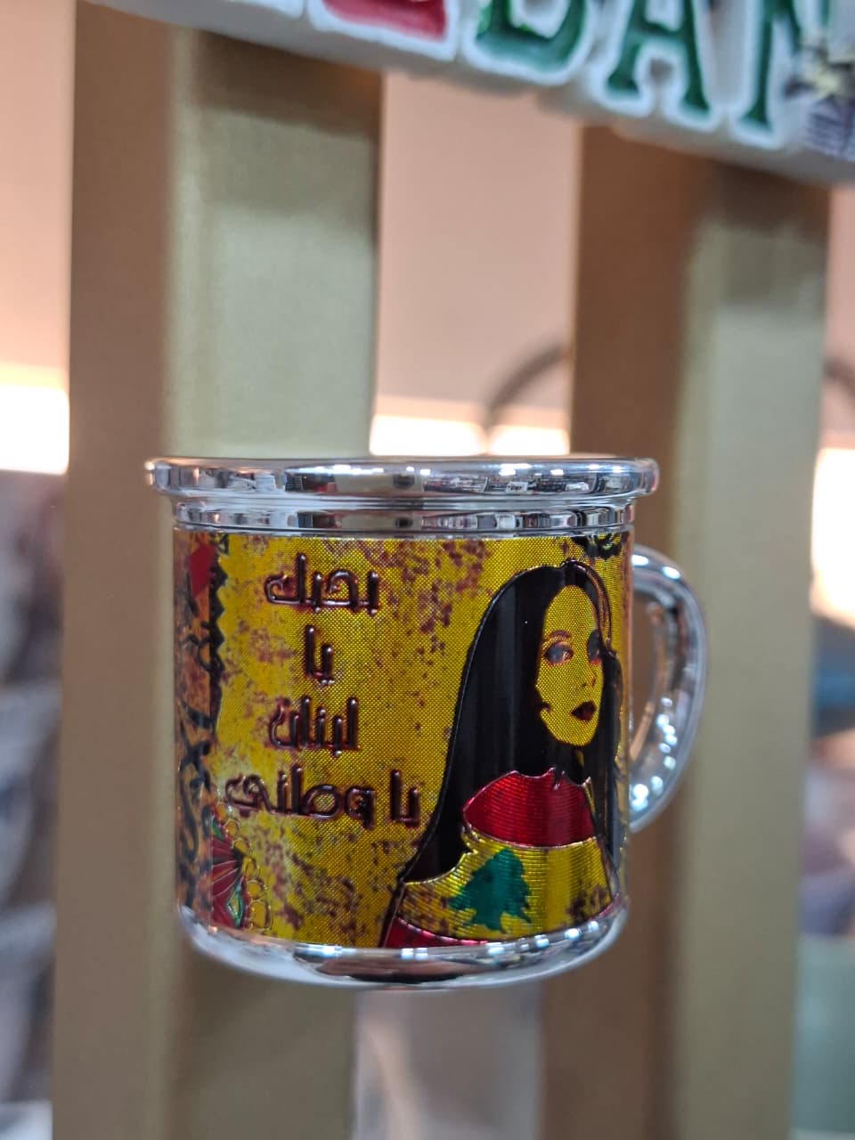 Decorative glass mug with a colorful design and text on a blurred background
